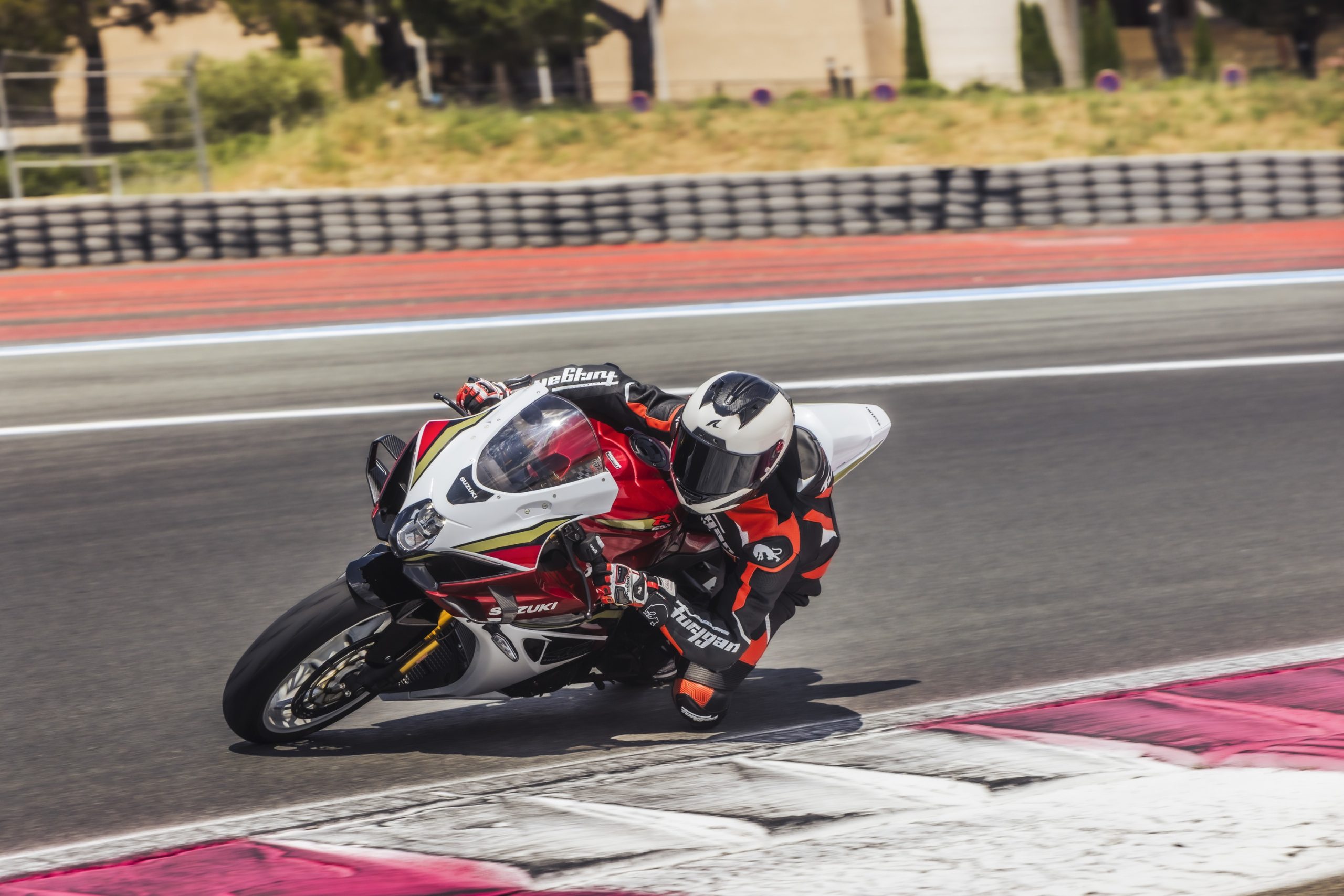 A Suzuki GSX-R1000R de 2026, vermelha e branca, em circuito, numa fotografia oficial da Suzuki. É a moto de série, não a dos Metzeler Sportec 01 RS.